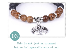 Detailed shot of tree of life charm on wood and volcanic stone beaded bracelet