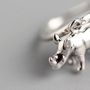 Macro shot of polished S925 sterling silver rhinoceros charm on a minimalist geometric earring