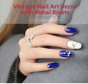 Detail of vintage gold alloy metal nail studs in moon and star shapes on dark blue nails