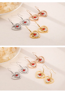 Detail von Herz-Ohrringen mit Cartoon-Motiven und roten Steinen in Silber und Gold