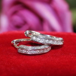 Macro shot of U-shaped pavé cubic zirconia hoop earrings on a luxury red velvet box