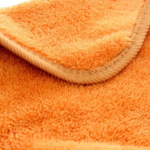 Macro shot of orange coral fleece fabric showing soft fibers and fine edge stitching