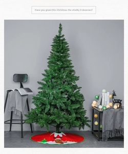 Classic green artificial Christmas tree with red reindeer patterned decorative tree skirt