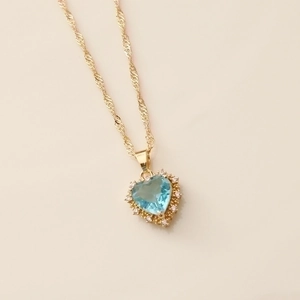 Gold heart necklace with sky blue gemstone and crystal border on a wavy chain
