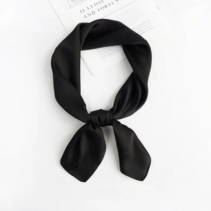 Detailed view of a black silk scarf tied in a knot, smooth satin texture on white background