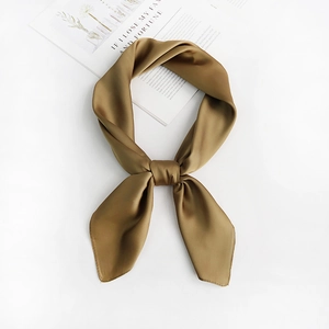 Detail of a brown silk-like square scarf tied in a knot on a white table backdrop