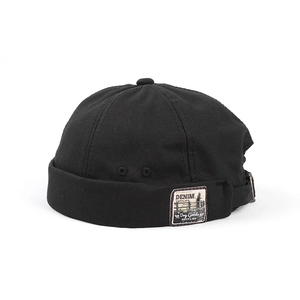 Detail of black retro docker hat showing vintage fabric patch and adjustable metal buckle