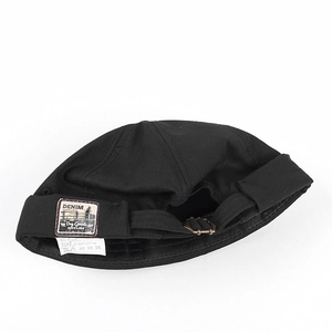 Detail of adjustable metal buckle strap and vintage patch on black cotton docker hat