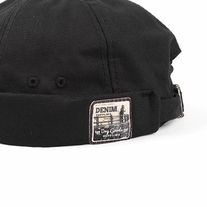 Detail of vintage black canvas docker hat with retro letter patch and metal eyelets