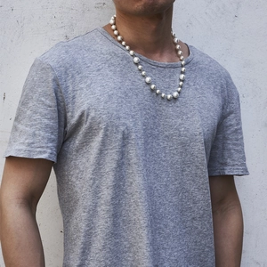 Hip hop titanium steel necklace featuring spliced white pearls on a male model in grey