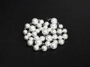Detail of silver chain and white pearl necklace with glossy finish on black background