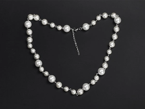 Detail of hiphop pearl necklace with silver lobster clasp and extension chain on black