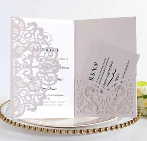 Detailed close-up of pink laser-cut wedding invitation set with R.S.V.P. card and white rose