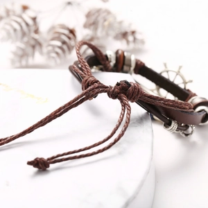 Vintage multilayer leather bracelet with turquoise and rudder charm on marble background