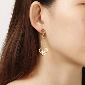 Gold tassel drop earrings with heart lock and crystal detail on a female model