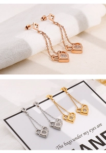 Detail of titanium steel lock dangle earrings with zircon in gold, silver, and rose gold