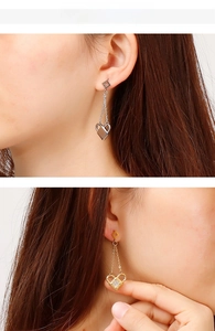 Detailed close-up of clover heart lock earrings featuring dangling tassels and crystals