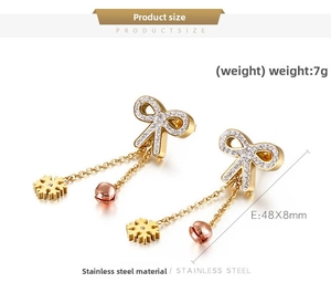 Detail of bowknot earrings in stainless steel with crystal accents and chain pendants