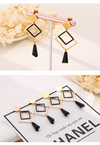 Detailed view of geometric titanium earrings with square links and black conical drops