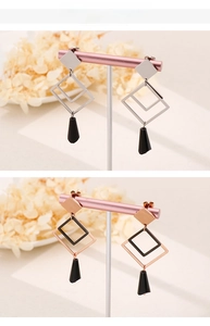 Detail view of geometric long drop earrings in silver and rose gold with square pendants