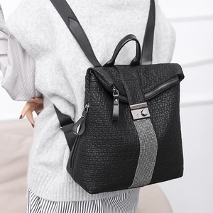 Close-up of black textured leather backpack with flap design and polished metal buckle