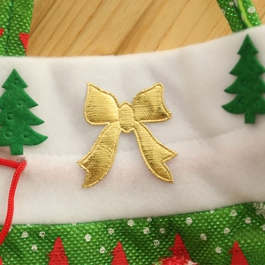Detailansicht einer Weihnachtstüte mit goldener Schleife und grüner Tannenbaum-Applikation.