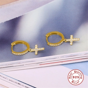 Macro view of gold S925 sterling silver cross hoop earrings with sparkling zircon stones