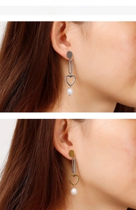 Detail of long heart drop earrings with white pearls in gold and silver finishes