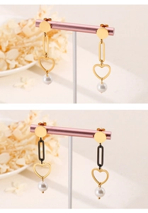 Detail of long chain earrings with heart charms and pearls in gold and black finish