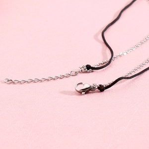 Fermoir mousqueton argenté et chaîne d'extension sur collier cordon noir sur fond rose