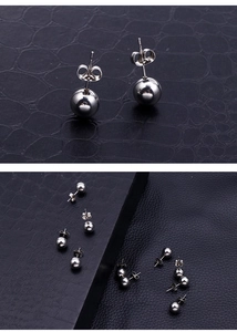 Detailed view of polished silver stainless steel ball stud earrings on black texture