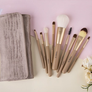 Flat lay of a 10-piece makeup brush set with pony hair bristles and a gold storage bag