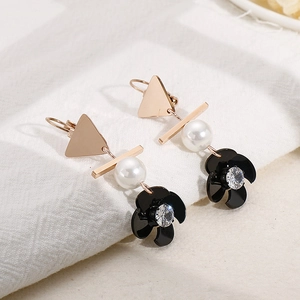 Boucles d'oreilles baroques dorées avec perles, fleurs noires et cristaux sur tissu blanc