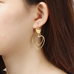 Golden double heart drop earrings on model, featuring a stylish minimalist layered metal design