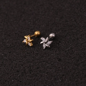 Macro detail of gold and silver flower stud earrings with zircon inlays and screw back