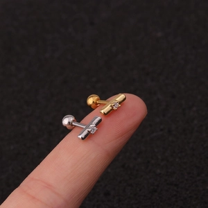 Close-up of small gold and silver screw-back crown earrings on a fingertip