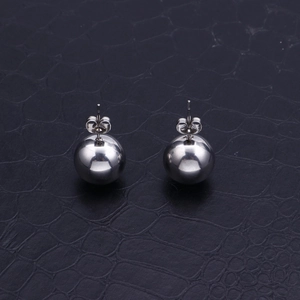 Polished silver stainless steel ball stud earrings on a textured dark background surface