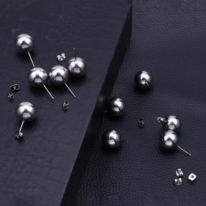 Minimalist stainless steel ball stud earrings in silver finish on textured black surface
