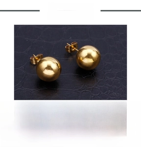 Macro shot of 18k gold plated stainless steel ball earrings on luxury leather texture