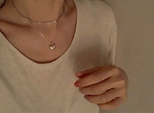 Macro shot of 925 silver layered heart pendant necklace and minimalist ring set