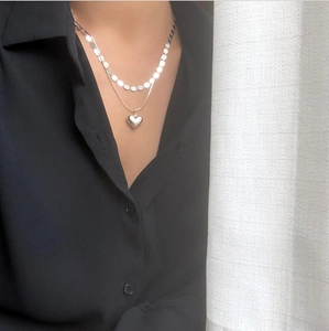 Close-up of double-layer silver necklace with heart pendant on model in black shirt