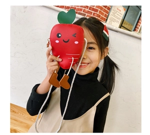 Close-up of cute red carrot-shaped kids crossbody bag with green heart leaves