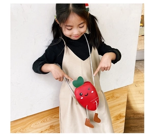 Close-up of cute carrot-shaped mini crossbody bag with cartoon eyes and boot charms