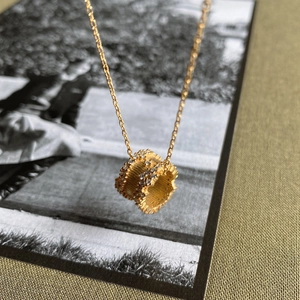 Macro shot of gold cylinder necklace pendant with bead edges and micro-set white zircon stones