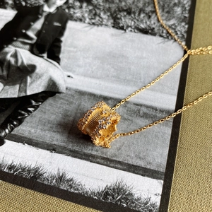 Close-up of gold 925 silver cylinder pendant with vertical stripes and white crystals