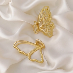 Set of two matte gold butterfly metal hair claws on elegant white silk background