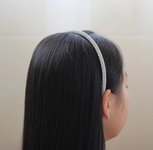 Detailed view of silver rhinestone headband on long black hair for a glittering fashion look