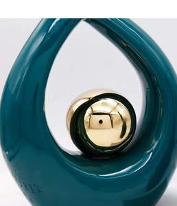 Detail einer blaugrünen Keramikskulptur mit goldener Kugel im modernen Luxusstil