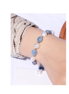 Detail of beaded bracelet with white pearls, blue gemstones, and gold spacer beads