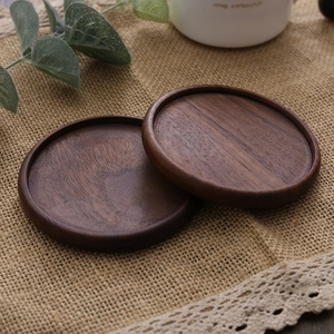 Two round walnut wood coasters with natural grain and smooth edges on burlap cloth
